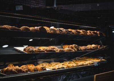 A variety of freshly baked pastries and breads in a glass display case at a bakery.